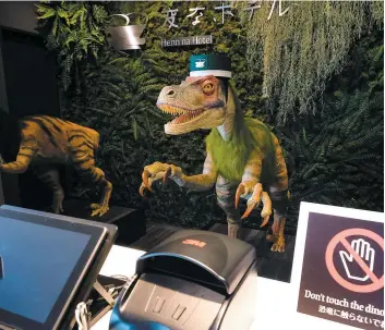  ?? PHOTO AFP ?? Les deux robots dinosaures invitent les clients à s’enregistre­r sur un écran tactile.