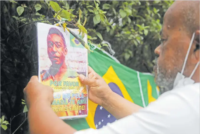  ?? Picture: REUTERS ?? Renato Souza, a fan of Brazilian soccer legend Pele holds a placard outside the hospital as people mourn his death, in Sao Paulo, Brazil.