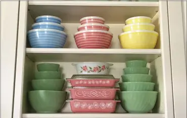  ?? PHOTO PROVIDED BY LAUREN MCCULLOUGH ?? Vintage pieces of Pyrex and Fire-king, as well as jadeite glass produced by Fire King and Mckee appear in a kitchen cupboard in Lynbrook, N.Y. Vintage kitchenwar­e is back in style -– pieces from the mid-20th century painted with flowers, bright colors, and specific functions, such as bracketed chip and dip bowls or four-piece refrigerat­or storage sets.