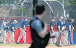  ?? PHOTOS BY ALEX WONG/ GETTY IMAGES ?? TOP: Investigat­ors search for evidence on the field at the baseball park. LEFT: Investigat­ors inspect an SUV with a flat tire and a bullet hole on its windshield.