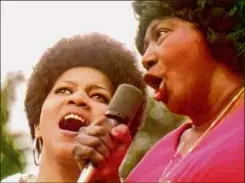  ??  ?? Sly Stone performing at the Harlem Cultural Festival in 1969, above, and Mavis Staples, left, and Mahalia Jackson performing at the festival in a scene from the documentar­y "Summer of Soul."