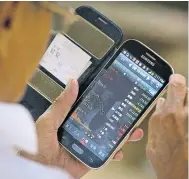  ?? AP ?? A Chinese investor uses his smartphone to monitor stock prices at a brokerage house in Beijing yesterday.