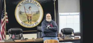  ?? ?? Ilion Mayor John Stephens poses for a picture in front of the seal of the village at the municipal building in Ilion, New York, U.S., Feb. 1, 2024.