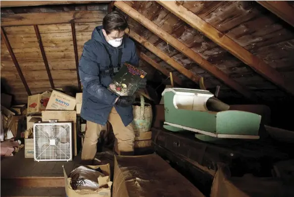  ?? DaviD BLOOm ?? Edmonton antique dealer Alex Archbold rummages through items left in the attic of a home he purchased recently in northeaste­rn Alberta.