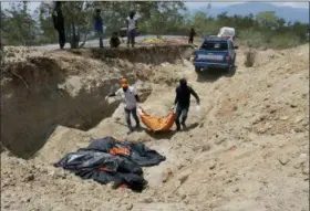  ?? DITA ALANGKARA — THE ASSOCIATED PRESS ?? Rescue workers carry a body to be buried at a mass grave for earthquake and tsunami victims in Palu, Central Sulawesi, Indonesia, Friday. A 7.5 magnitude earthquake rocked the city on Sept. 28, triggering a tsunami and mud slides that killed a large number of people and displaced tens of thousands others.