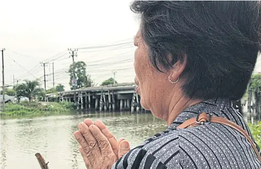  ??  ?? PRAYING FOR PEACE: Pornthip ‘Rung’ Kulnanun’s grandmothe­r prays where her young granddaugh­ter’s body was found in a Samut Prakan canal.