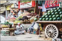  ??  ?? An Egyptian vendor reads the newspaper outside his fruit and vegetable stand in the Egyptian capital, Cairo, on May 15. Ramadan is a time for daytime fasting and lavish evening feasts, but Egyptians are scaling back preparatio­ns for the Muslim holy...