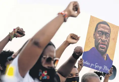  ??  ?? People raise their fists and hold a portrait of George Floyd during a rally in Atlanta, Georgia, U.S., April 20, 2021.