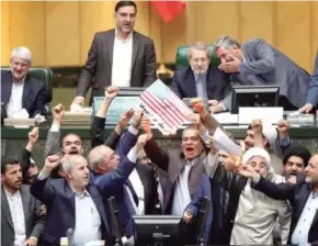  ??  ?? ▼ Miembros del parlamento iraní queman durante una sesión una bandera de EU.