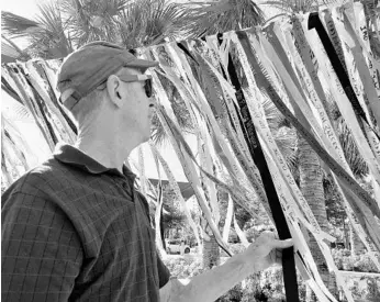  ?? RYAN GILLESPIE/STAFF ?? Jay Critchley, founder of the Provinceto­wn Community Compact, strings prayer ribbons outside of Orlando City Hall.