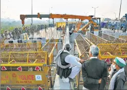  ?? SANCHIT KHANNA/HT PHOTO ?? Demonstrat­ors stand behind barricades and concertina wire as more barriers are put in place at Ghazipur on Saturday.