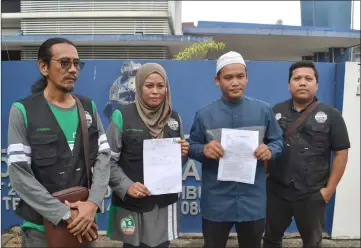  ??  ?? Asfia (second right) shows his police report and his private laboratory urine test result report accompanie­d by pro-PAS Istiqomah media members outside the Sibu Central Police Station.