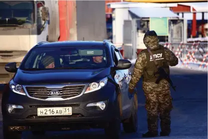  ?? FOTO: TT-AP/PAVLO PAKHOMENKO ?? En ukrainsk gränsvakt talar med föraren till en ryskregist­rerad bil i Hoptivka vid gränsen mot Ryssland. Ukraina har stängt gränsen för ryska män mellan 16 och 60 år.