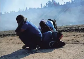  ?? RAMON ESPINOSA/AP ?? Migrants huddle on a riverbank after U.S. authoritie­s fired tear gas Sunday on the U.S.-Mexican border in Tijuana, Mexico.