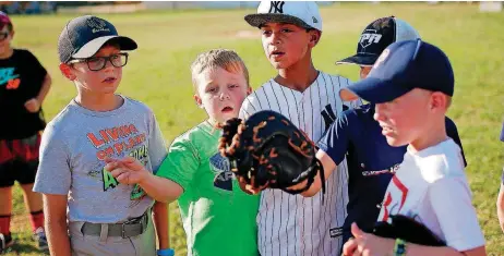  ?? [PHOTOS BY SARAH PHIPPS, THE OKLAHOMAN] ?? TOP: A player throws a pitch recently during a game of sandlot baseball in Edmond. ABOVE: Colton Roesslein, Carter Harris, Gator Chopski, Jake Subject and Hayden Frohling pick teams before a recent game of sandlot baseball in Edmond.