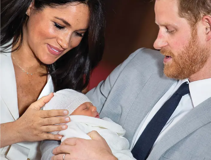  ??  ?? Doting: Prince Harry cradles Archie Harrison Mountbatte­n-Windsor yesterday as smiling new mother Meghan strokes her two-day-old son’s head