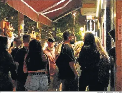  ?? M. ROMERO / PHOTOGRAPH­ERSSPORTS ?? Un grupo de jóvenes espera en la puerta de un establecim­iento de copas en Granada.