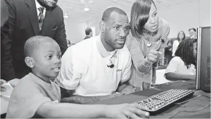  ?? LYNNE SLADKY/AP ?? LeBron James sits with Cam’ron Lightbourn­e at a new computer during a charity event at the Northwest Boys & Girls Club in Miami. The Cavaliers star’s foundation aims to assist youths and their families.
