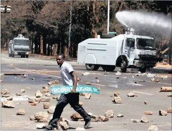  ??  ?? PROTEST: A man carries a street sign as opposition party supporters clash with police in Harare yesterday. PICTURE: REUTERS