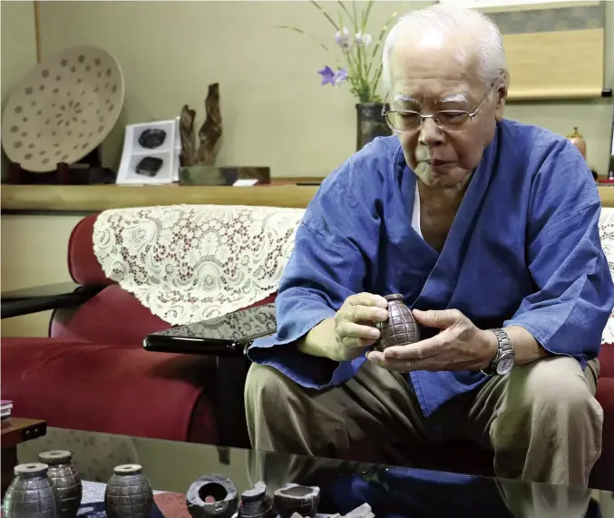  ?? Yomiuri Shimbun photos ?? Yuichi Yamamoto holds a Bizen hand grenade crafted during World War II by his father, in Bizen, Okayama Prefecture.