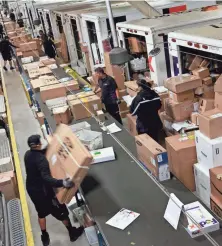  ?? TNS FILE PHOTO ?? FedEx worker Alejo Pasion unloads packages from an airplane container to a conveyor belt during the holiday shopping season.