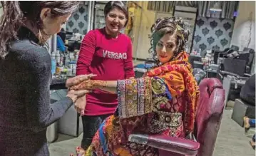  ??  ?? In this photograph, an Afghan beautician applies eye make-up for a client at a beauty parlour in Kabul. In this photograph, Afghan beautician­s affix jewelry to the hairstyle of a bride ahead of her wedding party at a beauty parlor in Kabul. — AFP...