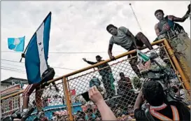  ?? JOHN MOORE/GETTY ?? Migrants scale a gate Friday separating Guatemala and Mexico. A caravan of migrants, mostly Hondurans, is trying to pass into Mexico en route to the United States.