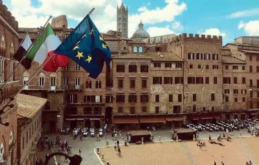  ??  ?? Le bandiere alle trifore di Palazzo Pubblico, la sede del Comune di Siena in piazza del Campo