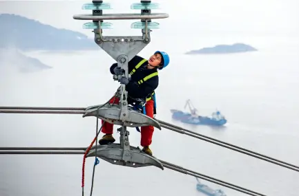  ??  ?? At a height of more than 300 meters above the sea, a female electricia­n conducts the final check before the wires are charged with electricit­y in Zhoushan, Zhejiang Province, on January 6, 2019. The Zhoushan 500-KV power transmissi­on network project is the main transmissi­on line of the Zhejiang FTZ.
