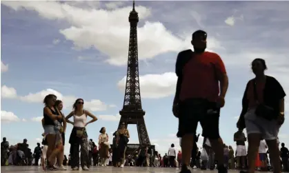  ?? Photograph: Mohammed Badra/EPA ?? People stand near the Eiffel tower at Place Trocadéro in Paris, France, on 12 August 2023.