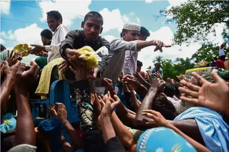  ?? — AFP ?? Dire times: Refugees gathering around a truck delivering food aid in Ukhia.