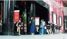  ?? — Reuters ?? Taking turns: People wearing face masks standing in line to enter a store at the shopping district of Orchard Road.