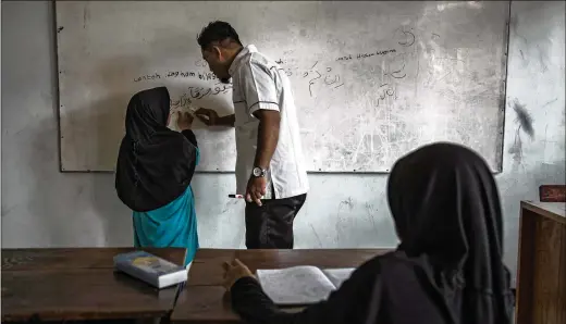  ?? PHOTOS BY ULET IFANSASTI / NEW YORK TIMES ?? Ais (left) writes in Arabic in a religious class in Jakarta, Indonesia, in April. Ais is part of a deradicali­zation program for children run by the Indonesian Ministry of Social Affairs. Her schoolmate­s include children of other suicide bombers, and of people who were intent on joining the Islamic State in Syria.