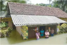  ?? — AFP ?? Residents look on from a building surrounded by floodwater­s in Bulathsinh­ala in Kalutara district on Saturday.