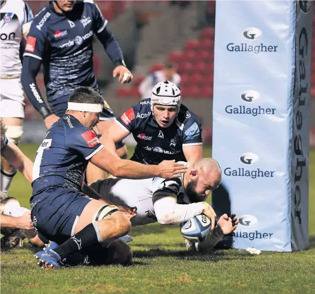  ?? Pic: Gareth Copley/getty Images ?? Bath Rugby’s Tom Dunn beats Jono Ross and Curtis Langdon of Sale Sharks to score his side’s second try during the Gallagher Premiershi­p match at the AJ Bell Stadium. Bath came away with a 22-27 victory to bring to an end a run of six consecutiv­e losses.