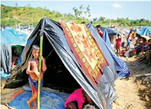  ??  ?? A Rohingya refugee boy looks on as he stands in his makeshift tent in Cox’s Bazar on Saturday. (Reuters)