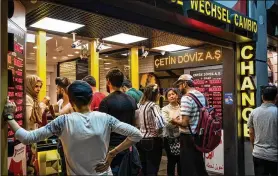  ?? NICOLE TUNG / BLOOMBERG NEWS ?? Tourists change money at an Istanbul currency bureau in August. The Turkish lira has lost more than 40 percent of its value this year.