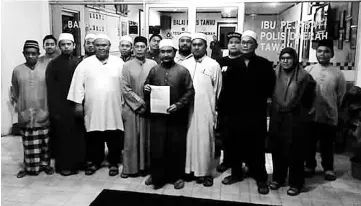  ??  ?? Members of Islamic NGOs pose with the police report on Wednesday night.