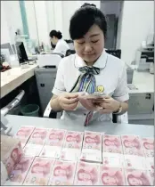  ??  ?? A clerk counts banknotes in a bank in Huaibei, China. The People’s Bank of China has relaxed some of the curbs on cross-border capital outflows it put in place just months ago.