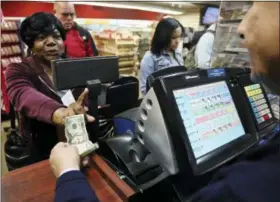  ?? BEBETO MATTHEWS — THE ASSOCIATED PRESS ?? Annette Gray, left, from Valley Stream, N.Y., buys lottery tickets Friday in New York. The estimated jackpot for Friday’s Mega Millions drawing has soared to $1 billion. Gray said it’s about “a dollar and a dream, but I spent ten today”.