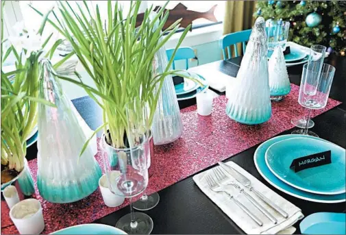 ?? KRISTINA CRESTIN PHOTOS ?? To add sparkle to a holiday table, interior designer Kristina Crestin paired raspberry-colored, metallic craft paper as a table runner with plants in silver-toned pots.