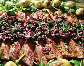  ?? PHOTO BY CATHY THOMAS ?? Flank steak can provide the robust flavor of beef at less cost than other cuts. Here, it’s topped with tapenade made with green and black olives.