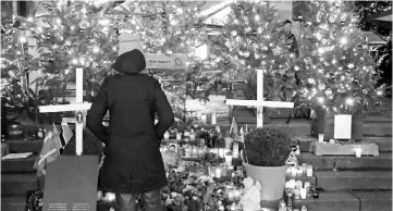  ??  ?? A woman watches a memorial at a Christmas market on Breitschei­dplatz square on the eve of the one year anniversar­y of a truck attack that killed 12 people and injured many others, in Berlin. — Reuters photo