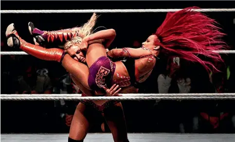  ?? GETTY IMAGES ?? Charlotte Flair takes down Sascha Banks in their match during the WWE Live Munich event in 2016. Donald Trump was an early backer of Wrestleman­ia, which has parallels with American politics.