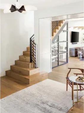  ??  ?? (right)
After altering the orientatio­n of the entryway, Deborah and Kristine opened up these once-enclosed stairs. “We removed side walls, added a custom iron railing, installed solid wood treads and risers to match the new hardwood and created a welcoming bottom landing,” Kristine says. Under the stairs, they put in a wine storage area, another nod to farmhouse functional­ity.