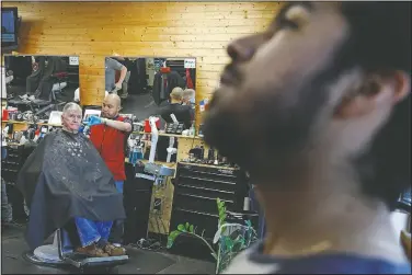  ??  ?? John Paul Garcia (right), 20, waits for his turn March 12 at the barber shop, Blast Barber Studio/Barberia, in Burlington, N.C.