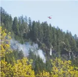  ?? MIKE BELL ?? As helicopter­s drop water on wildfires, such as this one above Squamish Valley Road last month, a new digital registrati­on system will speed services for evacuees and enable social distancing.