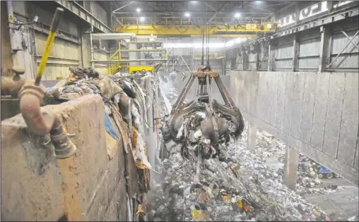  ??  ?? Operators control large grappling hooks to move garbage into a chute where the waste falls into the incinerato­r to burn during a tour of the Lancaster County Solid Waste Management Authority’s waste-to-energy facility in Bainbridge, Pa.
(LNP newspaper/Suzette Wenger)