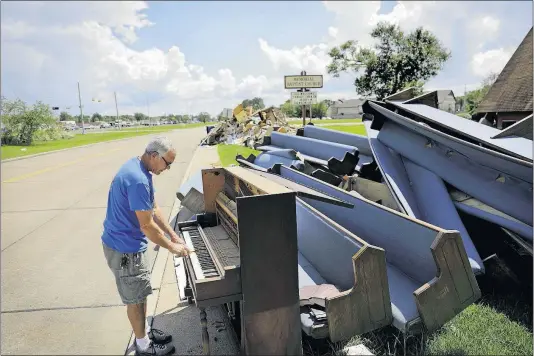  ?? [DAVID GOLDMAN/THE ASSOCIATED PRESS PHOTOS] ?? Wayne Christophe­r plays a piano that was waterlogge­d and put to the curb in Port Arthur, Texas. Christophe­r helped clear the piano and mountains of other items out of his church after Hurricane Harvey hit the area in September.