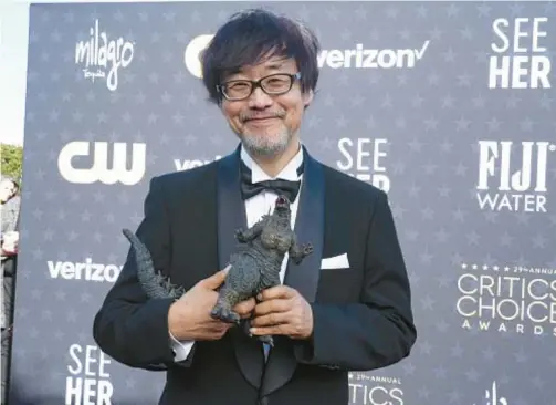  ?? JORDAN STRAUSS/INVISION ?? Takashi Yamazaki, holding a figurine of the character Godzilla, arrives at the 29th Critics Choice Awards on Jan. 14 in Santa Monica, California.